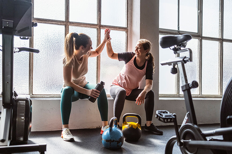 Zwei Frauen beim Gewichtstraining geben sich High Five.