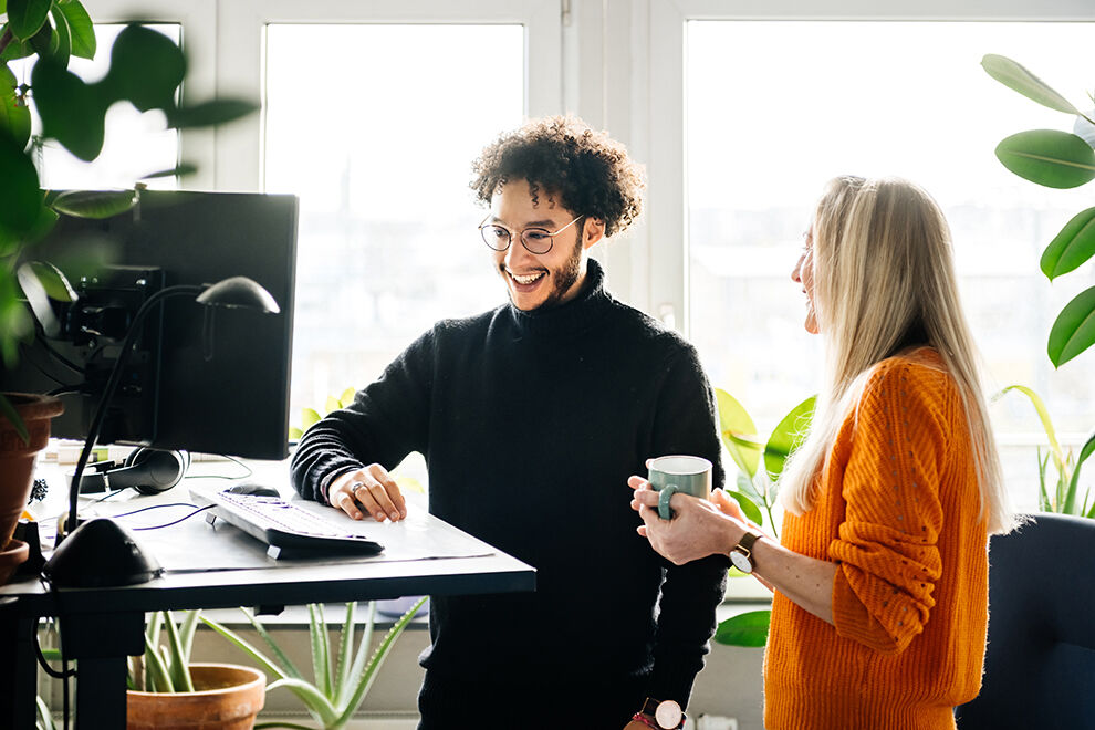 Zwei Personen stehen am höhenverstellbaren Schreibtisch
