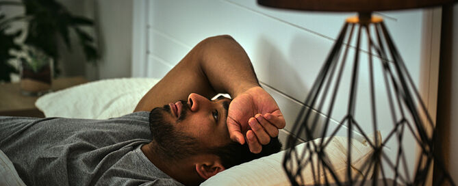 Person liegt wach im Bett