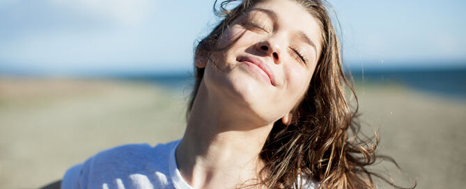 Junge Frau mit geschlossenen Augen lächelnd am Strand
