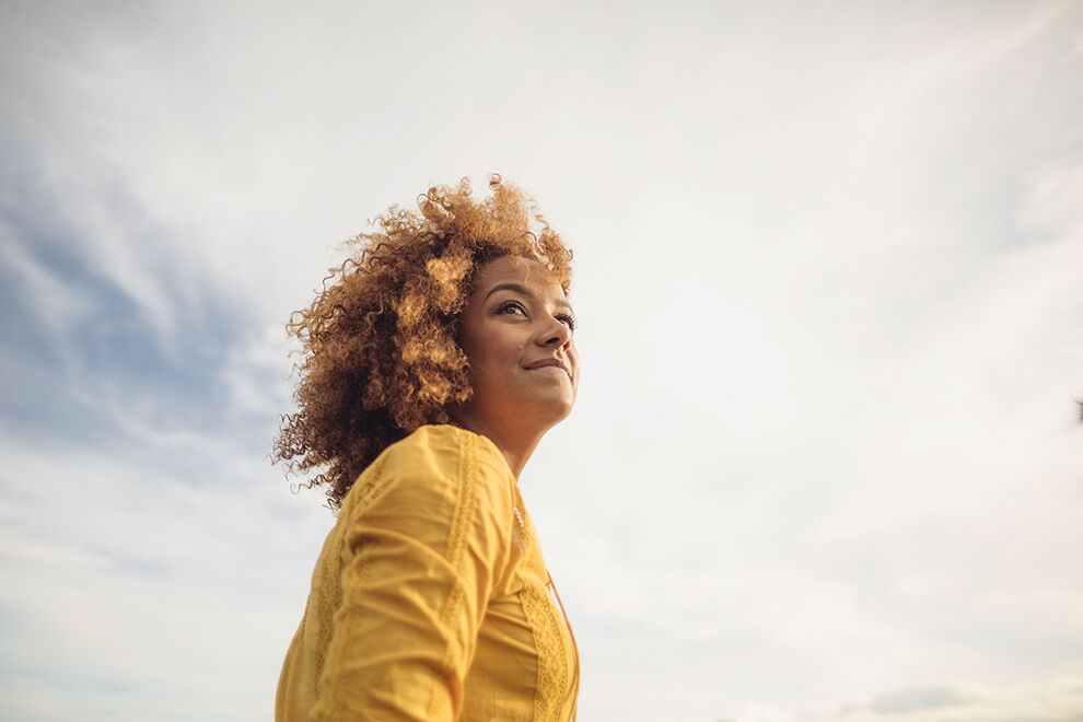 Portait einer Frau mit dem Himmel im Hintergrund.