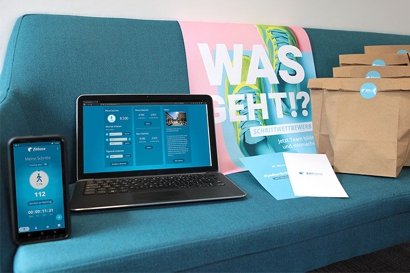 Fitbase Merchandise und Geräte mit aufgerufenen Webseiten des Schrittwettbewerbs.