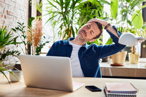 Ein Mann macht Rückenübungen am Schreibtisch