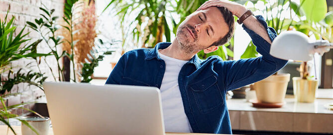 Ein Mann macht Rückenübungen am Schreibtisch