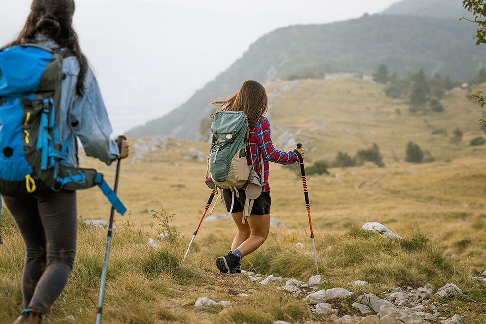 Zwei Wanderinnen mit Rucksäcken folgen einem Touristenpfad