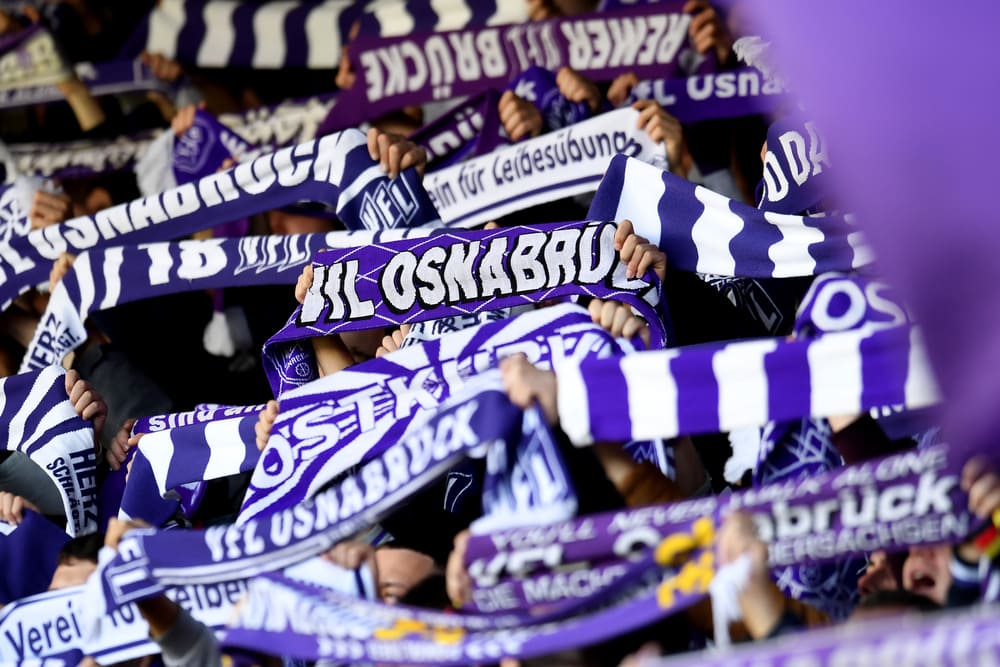 Die Fans vom VfL Osnabrück halten Schals und Hände in die Höhe