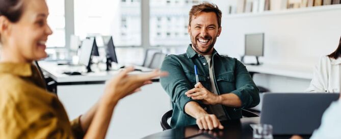 ein Mann und eine Frau sitzen an einem Schreibtisch und lachen