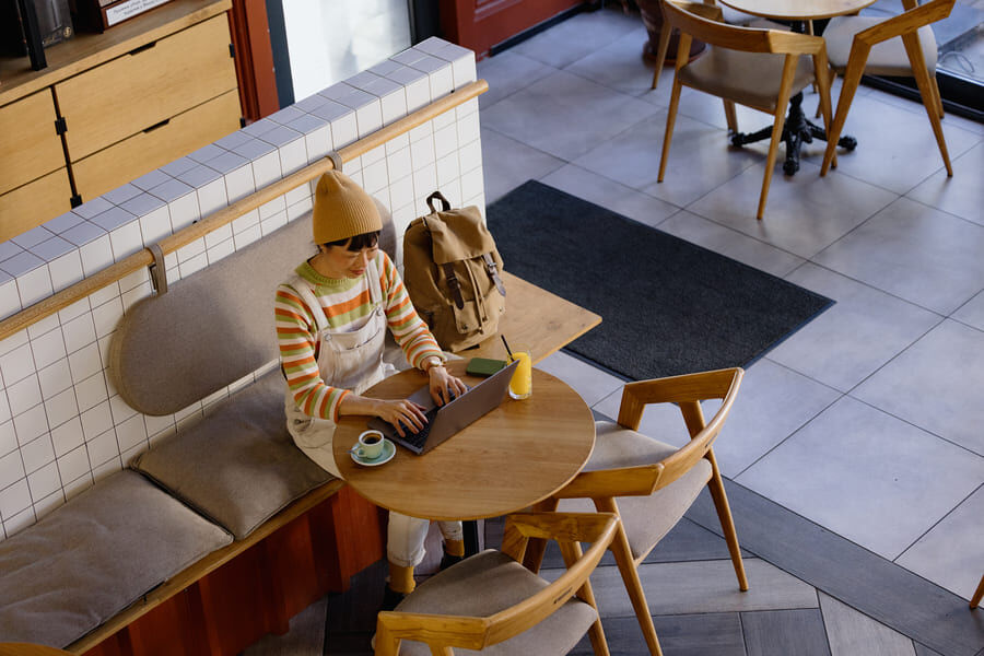 Hybrides Arbeiten: Eine Frau arbeitet an ihrem Laptop in einem Cafe