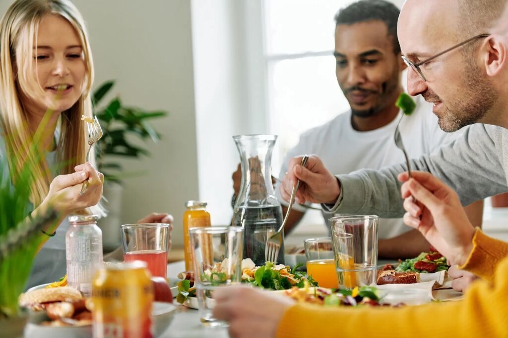 Eine Frau und zwei Männer sitzen an einem gedeckten Esstisch