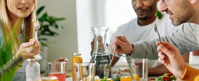 Eine Frau und zwei Männer sitzen an einem gedeckten Esstisch