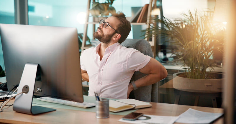 Ein Mann streckt sich etwas während er sich den Rücken hält.